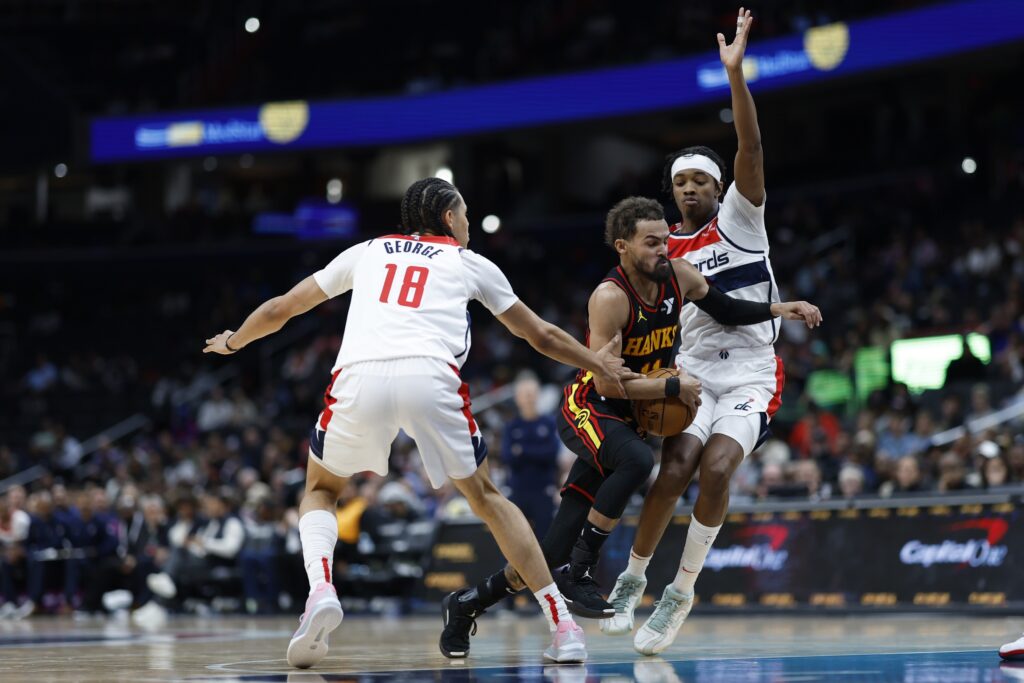 Oct 30, 2024; Washington, District of Columbia, USA; Atlanta Hawks guard Trae Young (11) drives to the basket as Washington Wizards forward Kyshawn George (18) and Wizards guard Bilal Coulibaly (0) defend in the first half at Capital One Arena. Mandatory Credit: Geoff Burke-Imagn Images